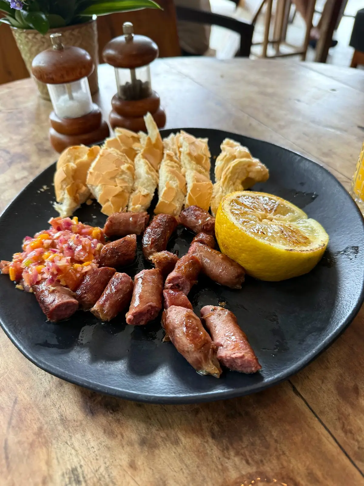 Prato com linguiça artesanal grelhada, pão de alho, vinagrete e limão grelhado